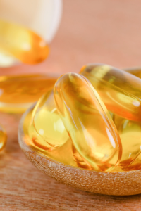 Close-up of translucent golden vitamin E capsules spilling onto a wooden surface, emphasizing health and supplementation